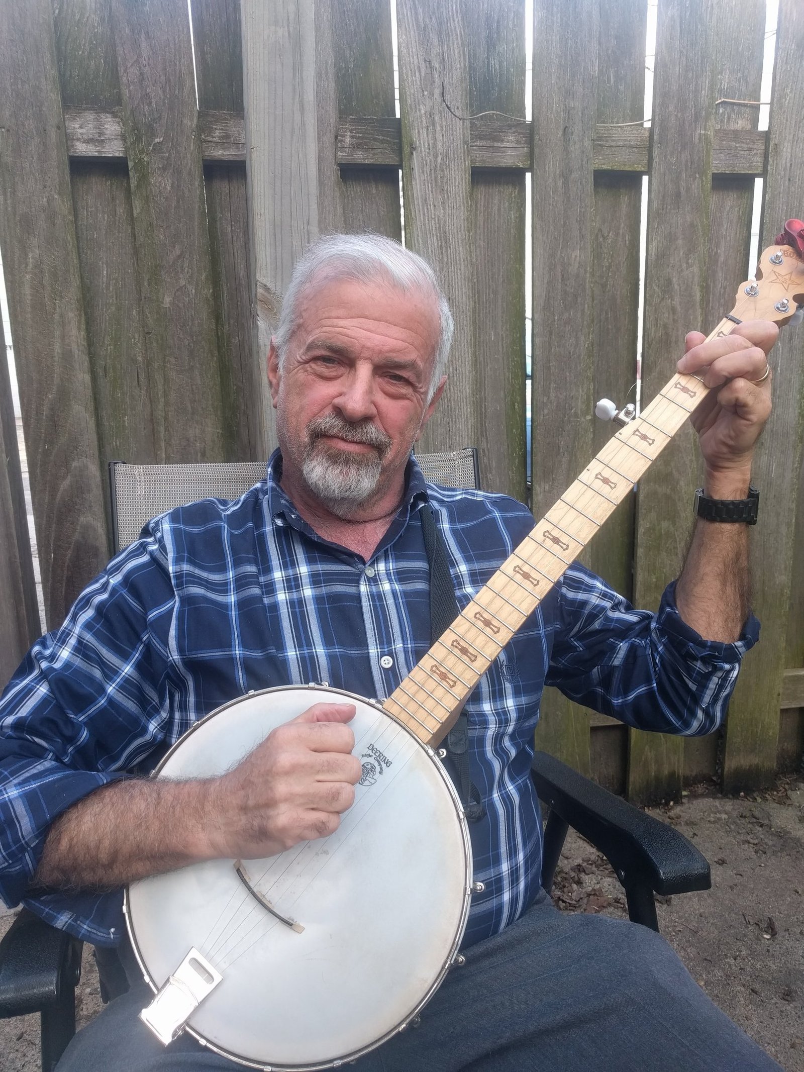 Jeremy Iggers sits outdoors and plays a five-string banjo.